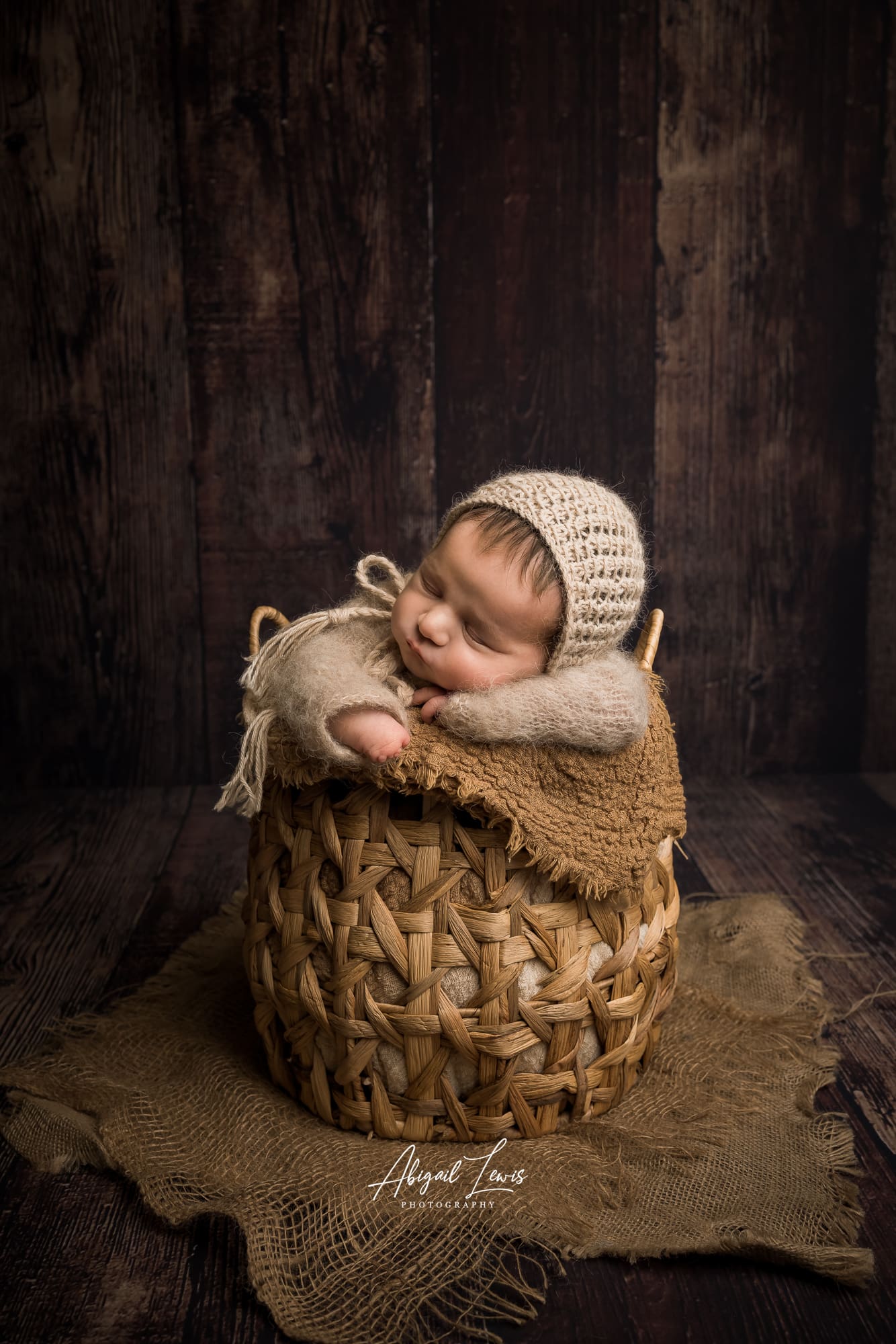 Newborn Baby in a honey pot basket on dark wooden background