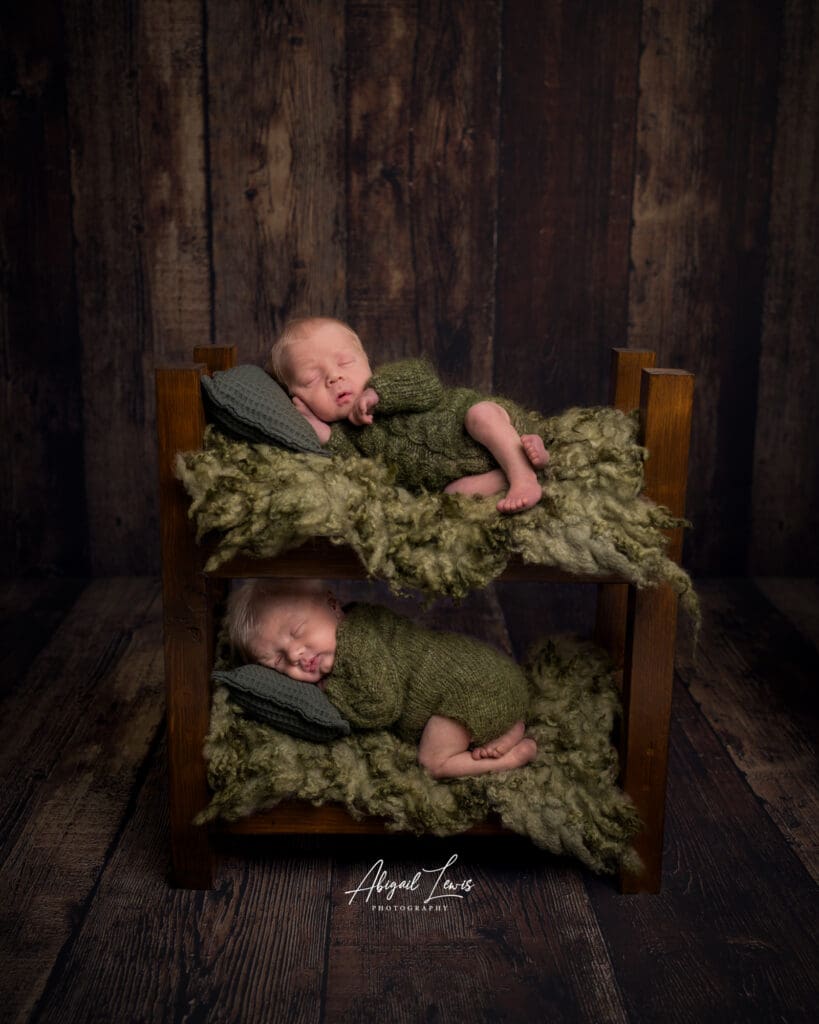 Newborn Twins posed in a bunk bed on a wooden background